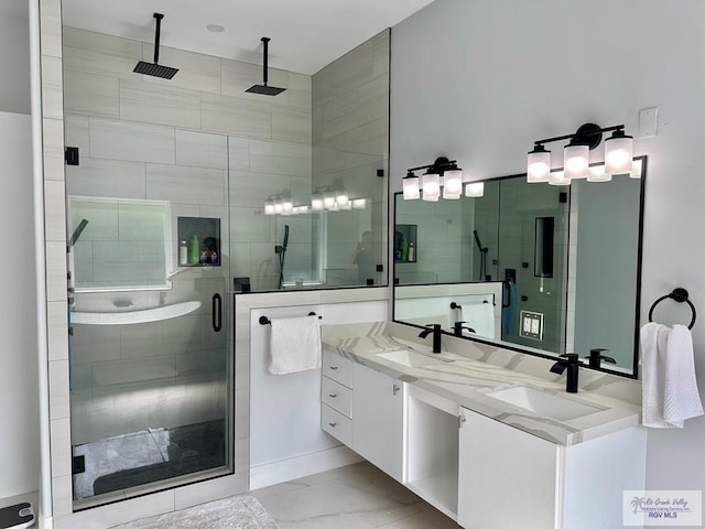 full bathroom featuring marble finish floor, double vanity, a sink, and a shower stall