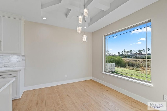 unfurnished dining area featuring coffered ceiling, beam ceiling, and light hardwood / wood-style flooring