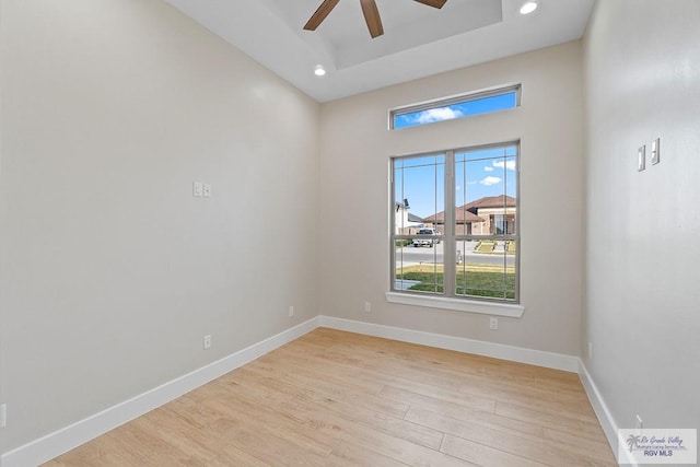 spare room with ceiling fan, a raised ceiling, and light hardwood / wood-style flooring