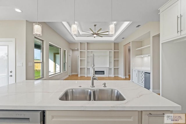 kitchen featuring decorative light fixtures, light stone countertops, sink, and dishwasher