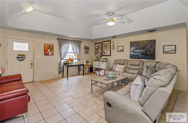 living room featuring a raised ceiling, ceiling fan, and light tile patterned flooring