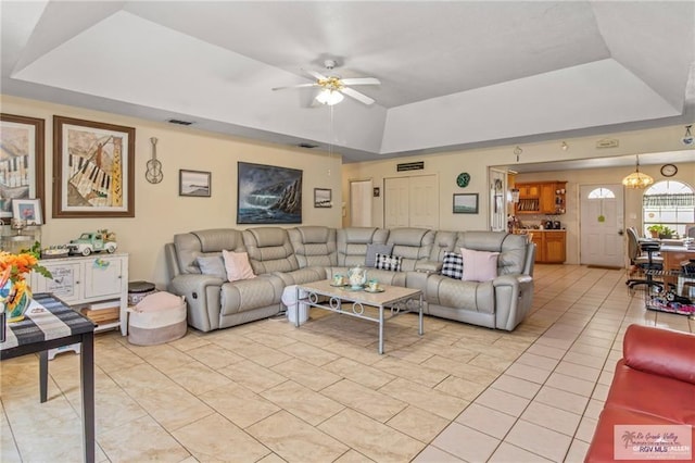 living room featuring light tile patterned floors, a tray ceiling, and ceiling fan