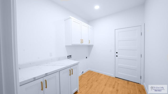 washroom with cabinets, light hardwood / wood-style flooring, and electric dryer hookup