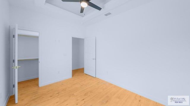 unfurnished bedroom with ceiling fan, a closet, a high ceiling, and light wood-type flooring