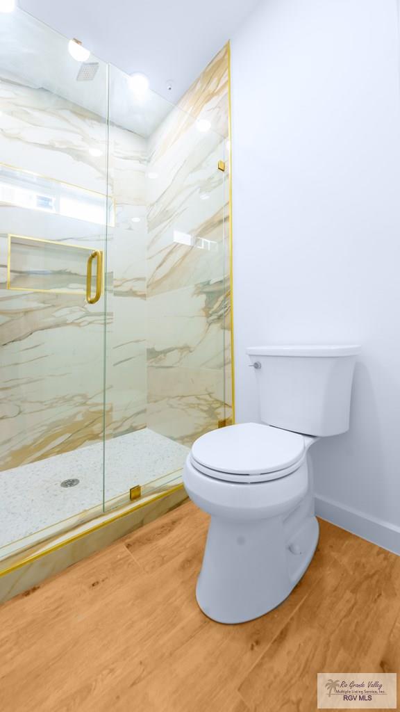 bathroom featuring walk in shower, hardwood / wood-style floors, and toilet