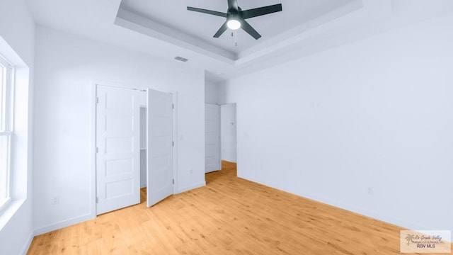 unfurnished bedroom featuring a tray ceiling and light hardwood / wood-style flooring