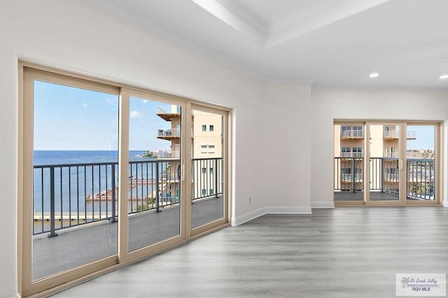 unfurnished room featuring hardwood / wood-style flooring, a water view, and crown molding