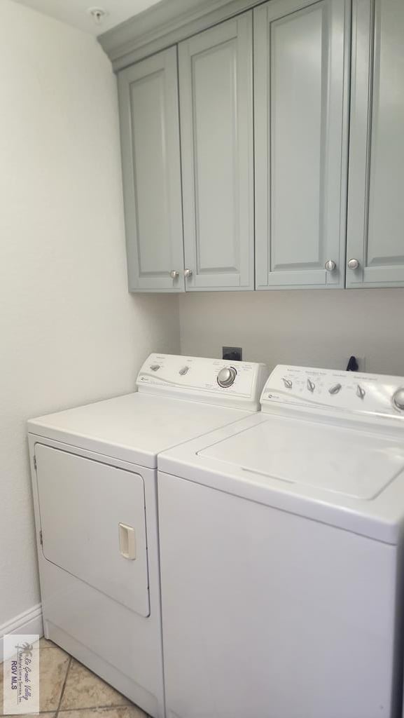 laundry room with washer and dryer, cabinets, and light tile patterned floors