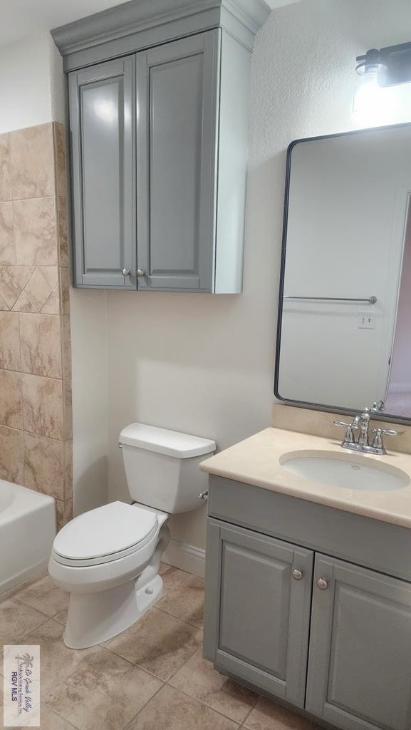 full bathroom featuring tile patterned floors, vanity, toilet, and washtub / shower combination