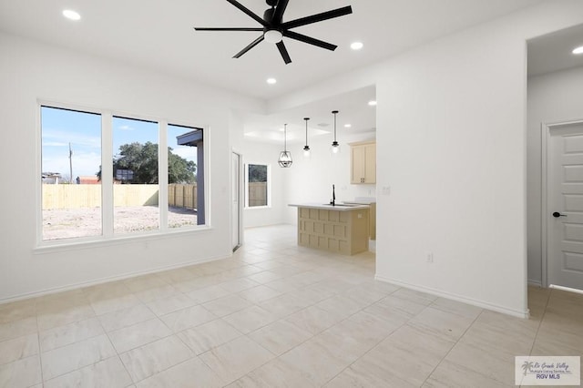 unfurnished living room with sink, light tile patterned floors, and ceiling fan