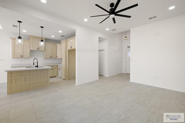 kitchen featuring ceiling fan, an island with sink, sink, and hanging light fixtures