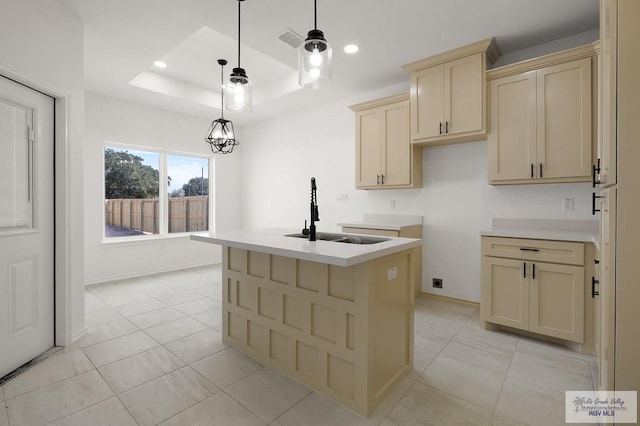 kitchen with sink, hanging light fixtures, a kitchen island with sink, light tile patterned floors, and a raised ceiling