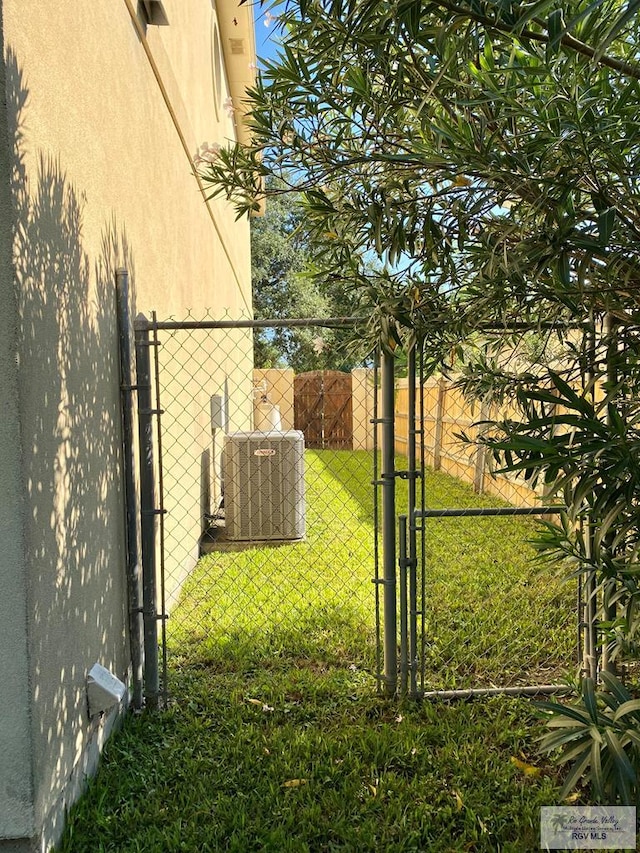 view of yard with central AC unit, fence, and a gate