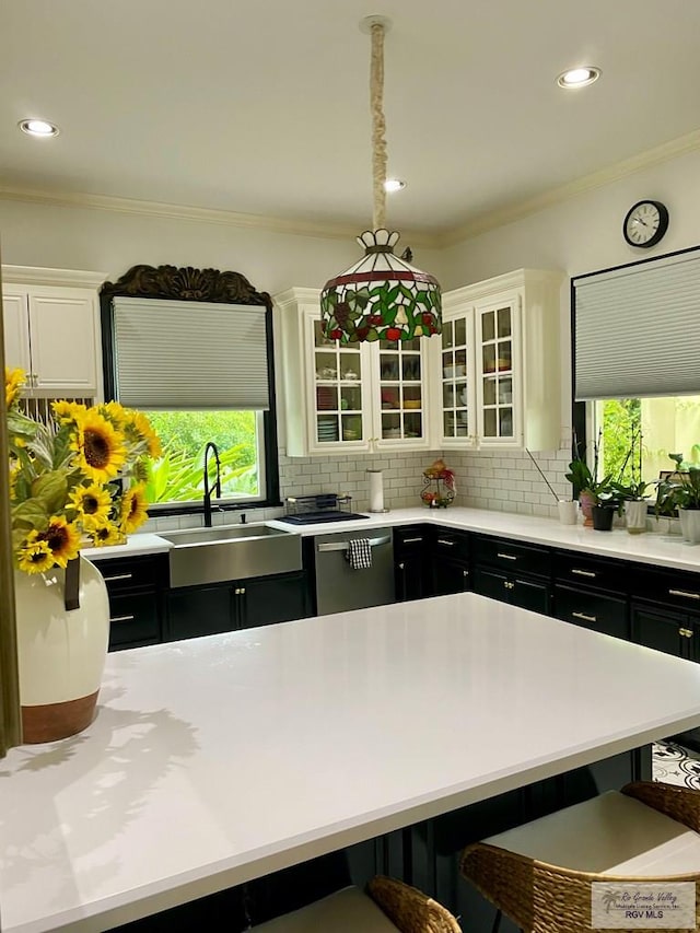 kitchen featuring stainless steel dishwasher, a sink, dark cabinetry, and a kitchen breakfast bar