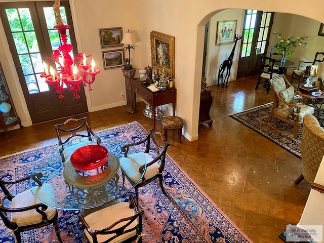 entrance foyer with arched walkways, french doors, a chandelier, and baseboards