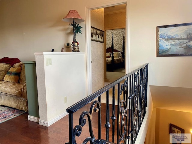 hall featuring baseboards, wood finished floors, and an upstairs landing