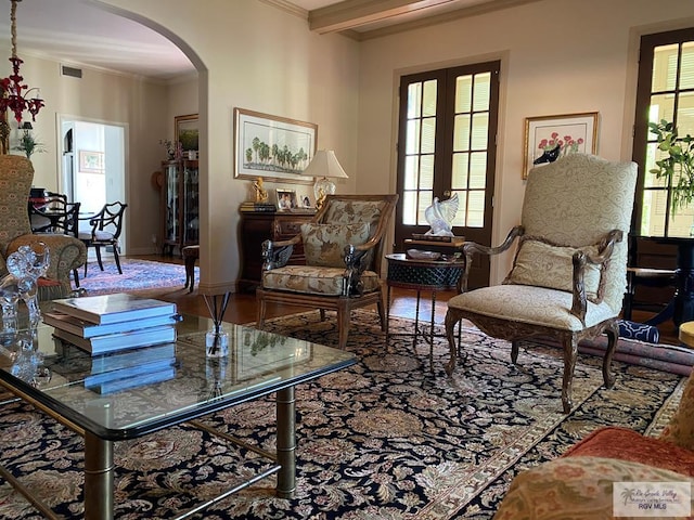 sitting room featuring arched walkways, visible vents, crown molding, and beamed ceiling