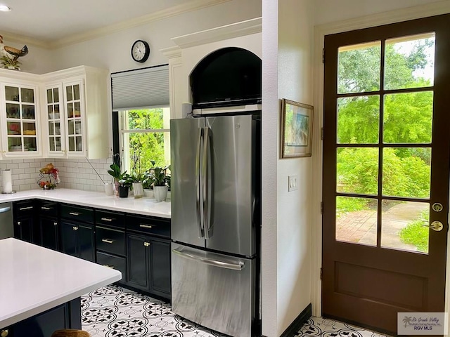 kitchen featuring light countertops, ornamental molding, appliances with stainless steel finishes, dark cabinetry, and backsplash