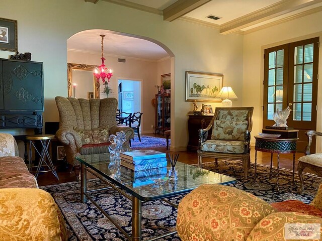 sitting room with hardwood / wood-style floors, french doors, an inviting chandelier, ornamental molding, and beam ceiling