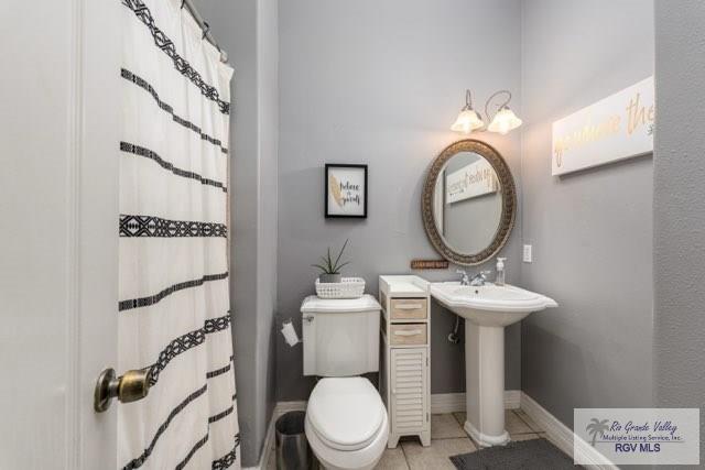 bathroom featuring a shower with curtain, sink, tile patterned floors, and toilet