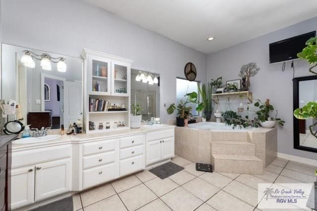 bathroom featuring tile patterned flooring, vanity, and a relaxing tiled tub