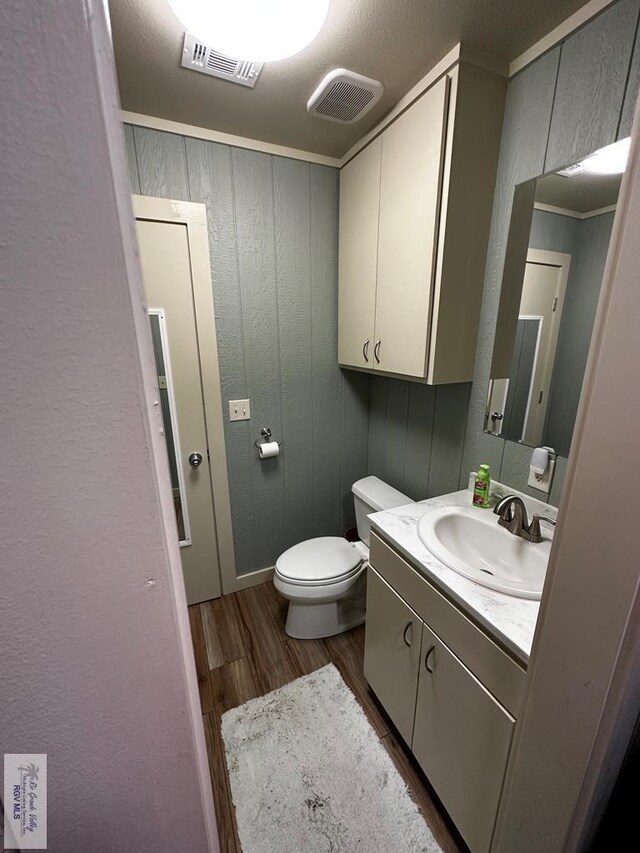 bathroom with vanity, a textured ceiling, crown molding, wood-type flooring, and toilet