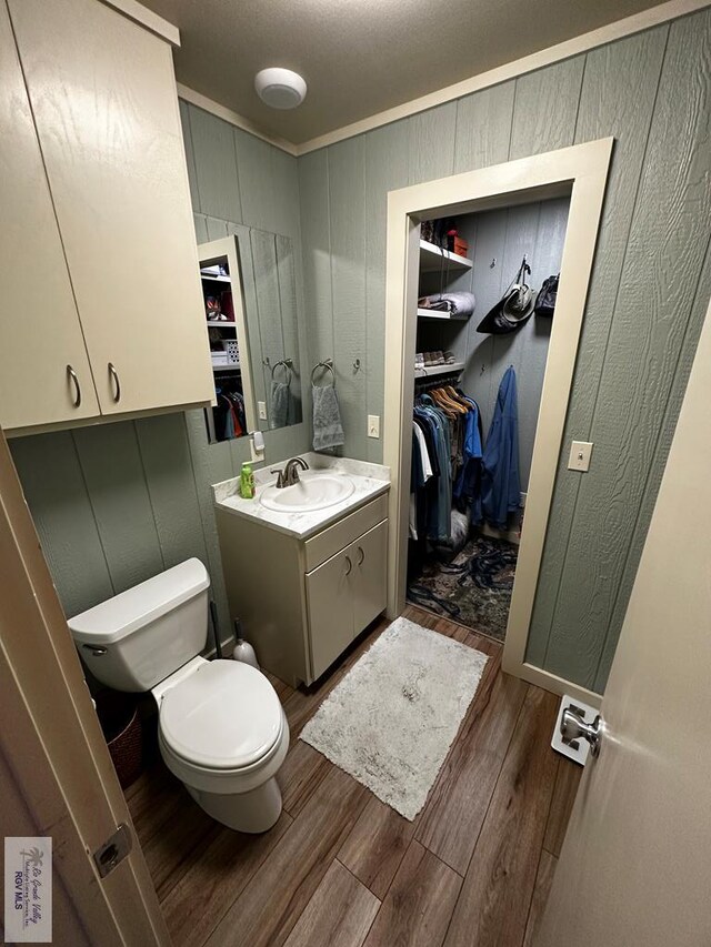 bathroom with vanity, toilet, wood-type flooring, and ornamental molding