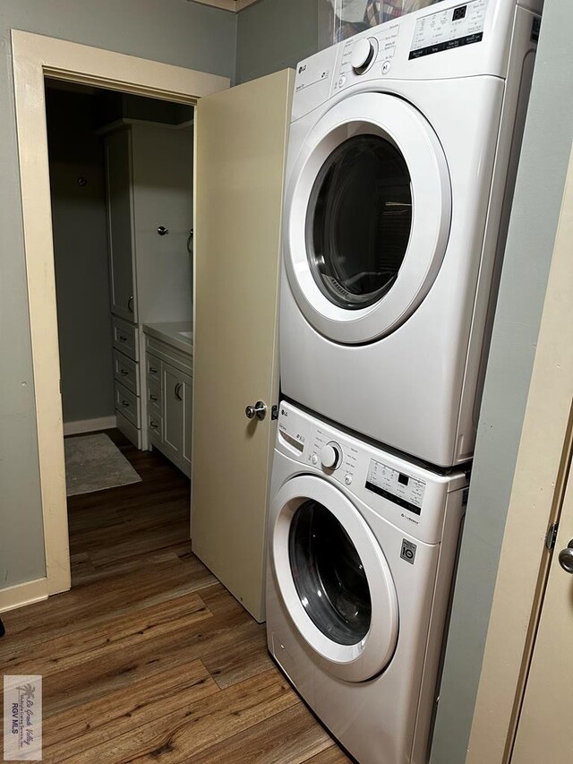 clothes washing area featuring dark wood-type flooring and stacked washer / drying machine