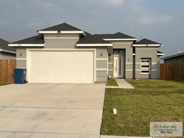 prairie-style home with a garage, concrete driveway, a front yard, and fence