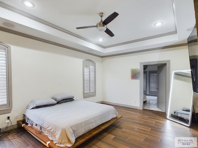 bedroom featuring dark hardwood / wood-style flooring, a tray ceiling, ceiling fan, and ornamental molding