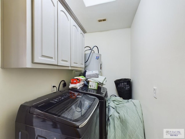 clothes washing area featuring cabinets, electric water heater, and washing machine and clothes dryer