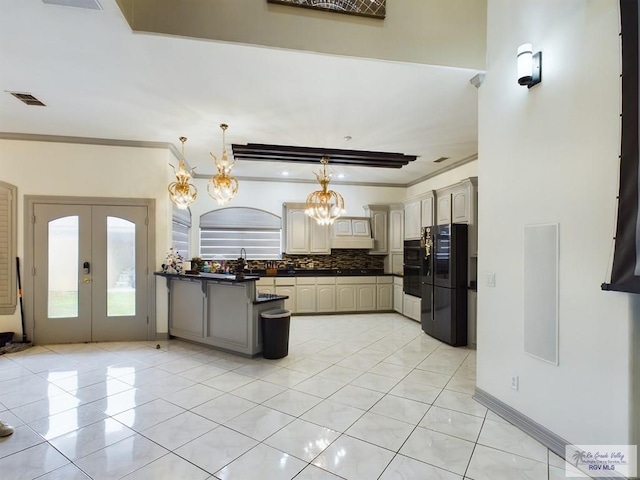 kitchen with black refrigerator, decorative backsplash, french doors, a notable chandelier, and hanging light fixtures