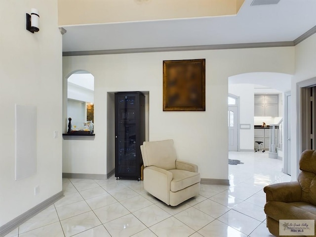 sitting room with light tile patterned floors, beverage cooler, and ornamental molding