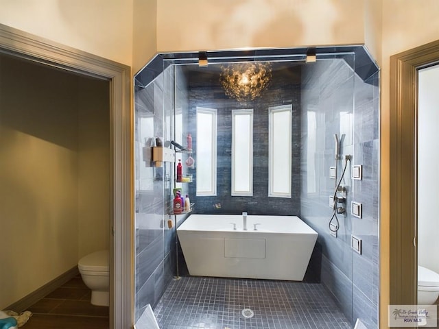 bathroom with a washtub, tile patterned floors, toilet, and tile walls