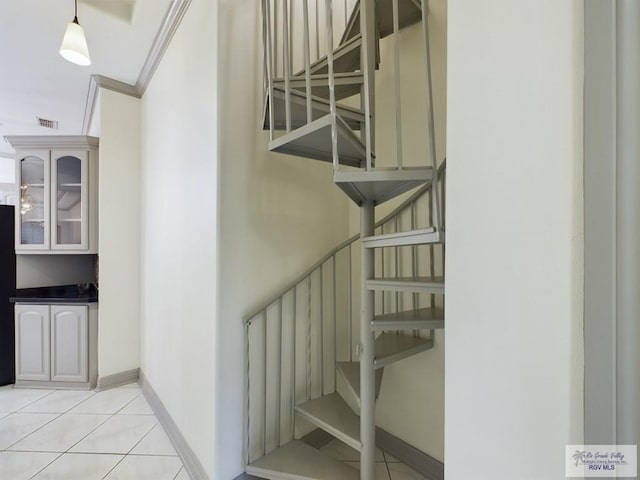 staircase with tile patterned floors and ornamental molding