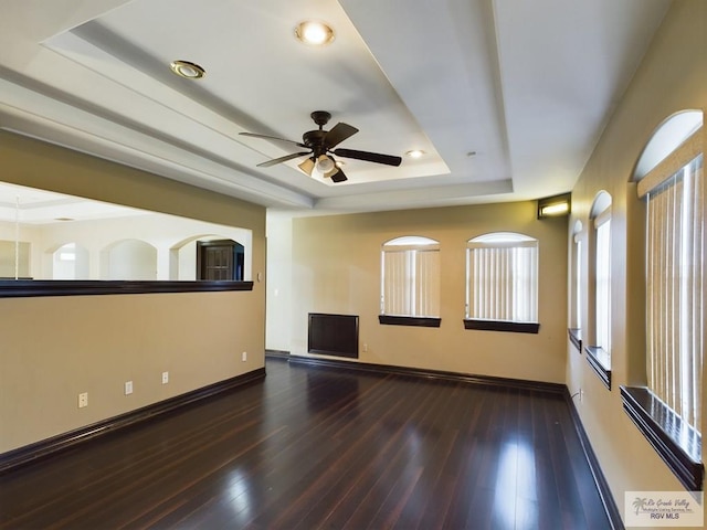 spare room featuring dark hardwood / wood-style flooring, a tray ceiling, and ceiling fan