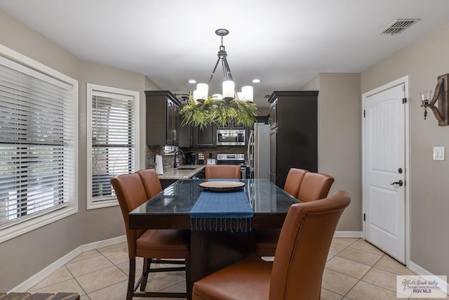 dining room with light tile patterned floors, baseboards, visible vents, and a chandelier