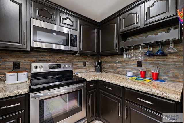 kitchen featuring appliances with stainless steel finishes, decorative backsplash, and light stone counters