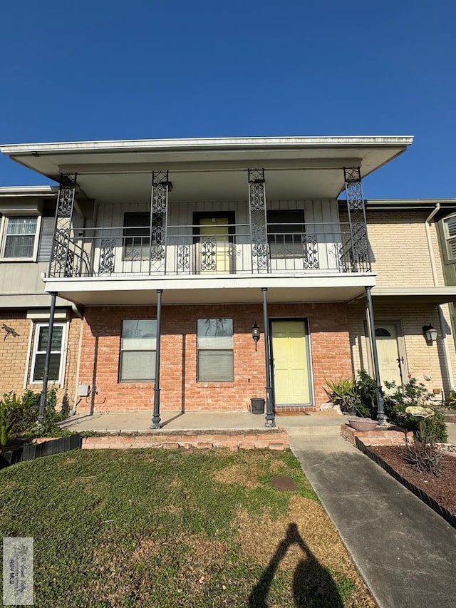 view of front of house featuring brick siding and a balcony