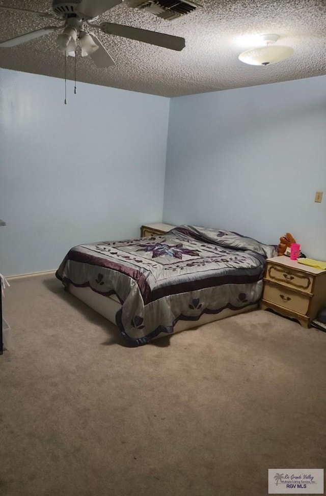 carpeted bedroom featuring visible vents, ceiling fan, and a textured ceiling