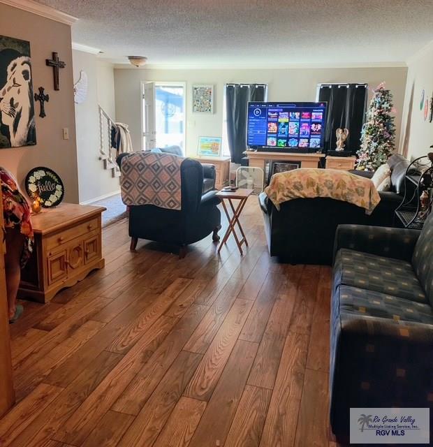 living room featuring ornamental molding, a textured ceiling, and hardwood / wood-style floors