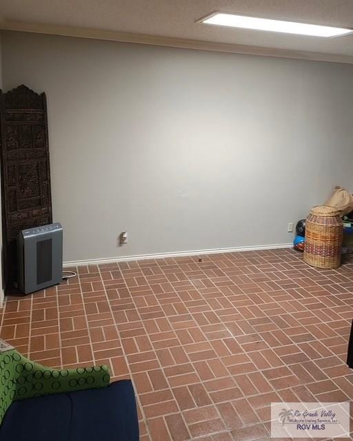 interior space with crown molding, brick floor, and baseboards