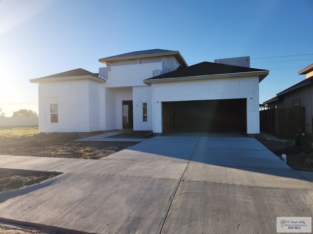 view of front of property with a garage, concrete driveway, and fence