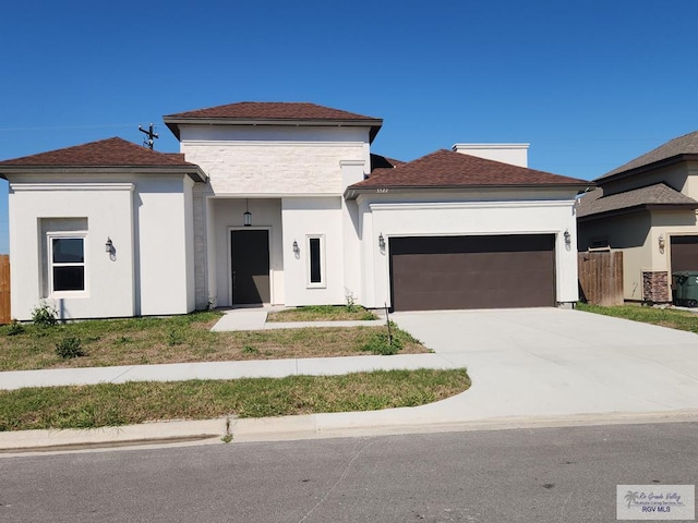 view of front facade featuring concrete driveway, an attached garage, fence, and stucco siding