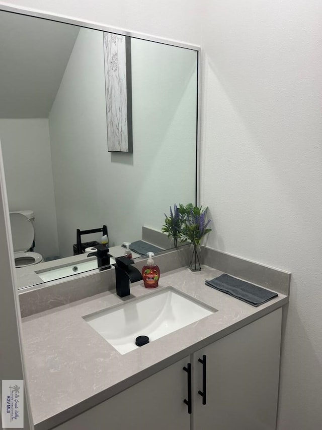 bathroom featuring vanity, toilet, and vaulted ceiling