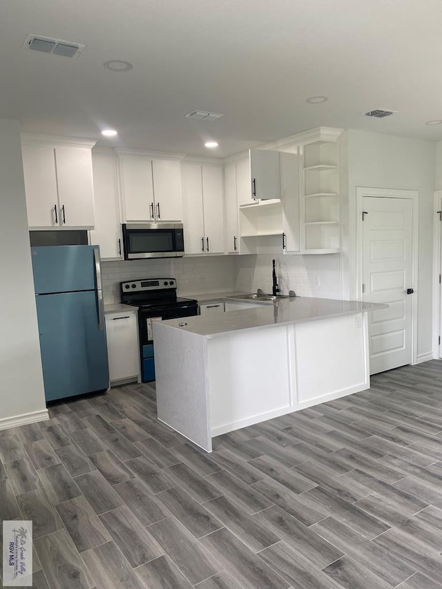 kitchen with white cabinets, wood-type flooring, and appliances with stainless steel finishes