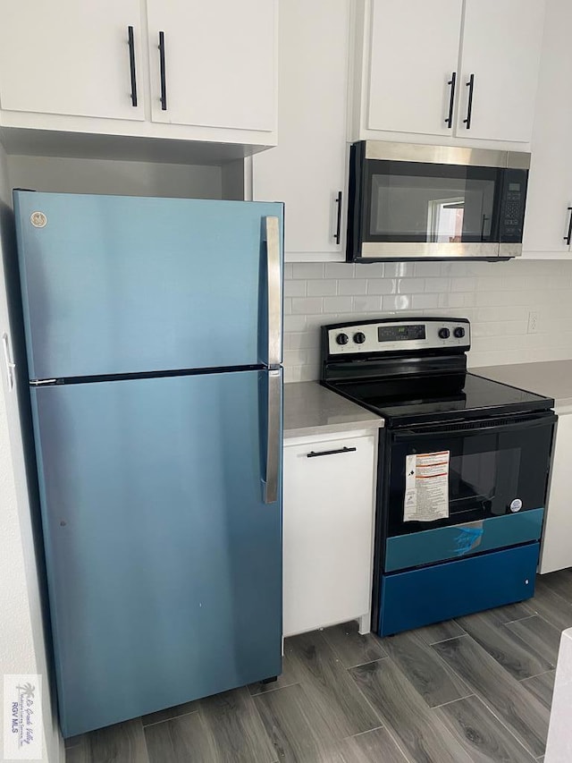 kitchen with backsplash, white cabinets, dark wood-type flooring, and appliances with stainless steel finishes