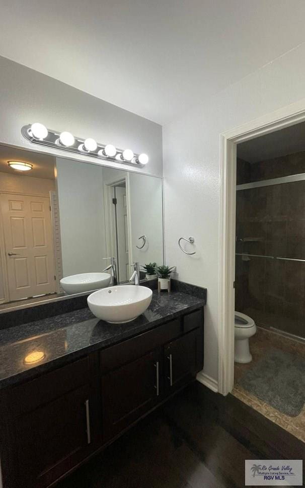 bathroom with hardwood / wood-style flooring, vanity, toilet, and an enclosed shower