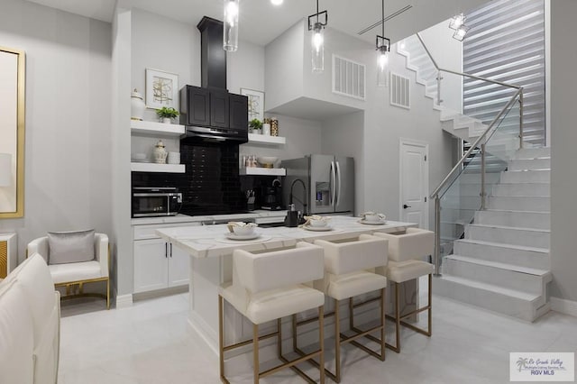 kitchen with decorative light fixtures, a kitchen island with sink, appliances with stainless steel finishes, and a breakfast bar area