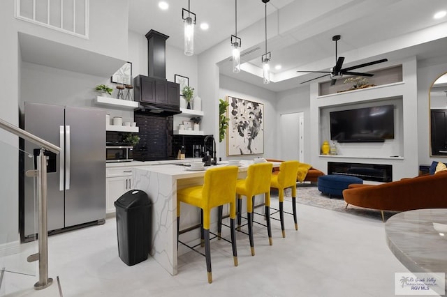 kitchen featuring ceiling fan, decorative backsplash, appliances with stainless steel finishes, decorative light fixtures, and a kitchen bar